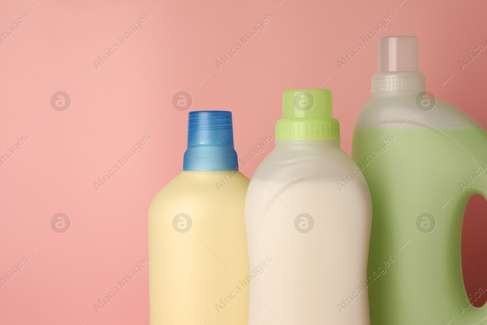 Photo of Bottles of fabric softener on pink background, space for text