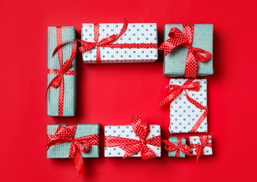 Photo of Frame of Christmas gift boxes on bright red background, flat lay. Space for text