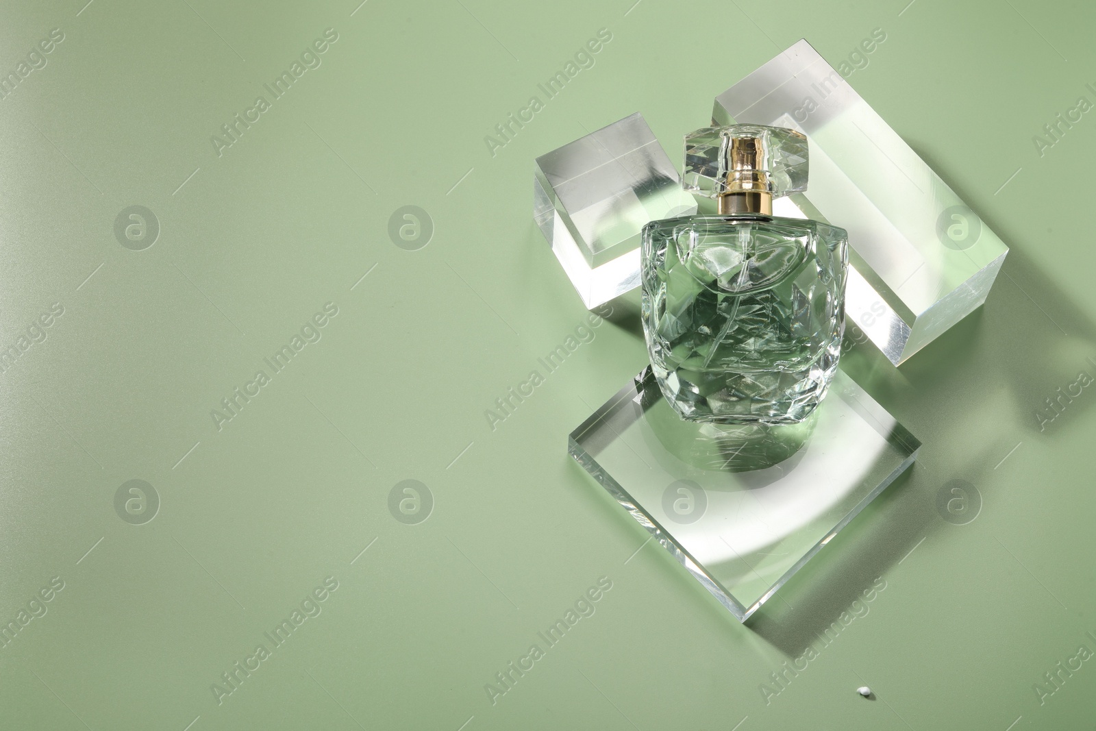 Photo of Stylish presentation of luxury perfume in sunlight on olive background, above view. Space for text