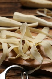 Photo of Peeled fresh parsnips and strips on wooden table, closeup