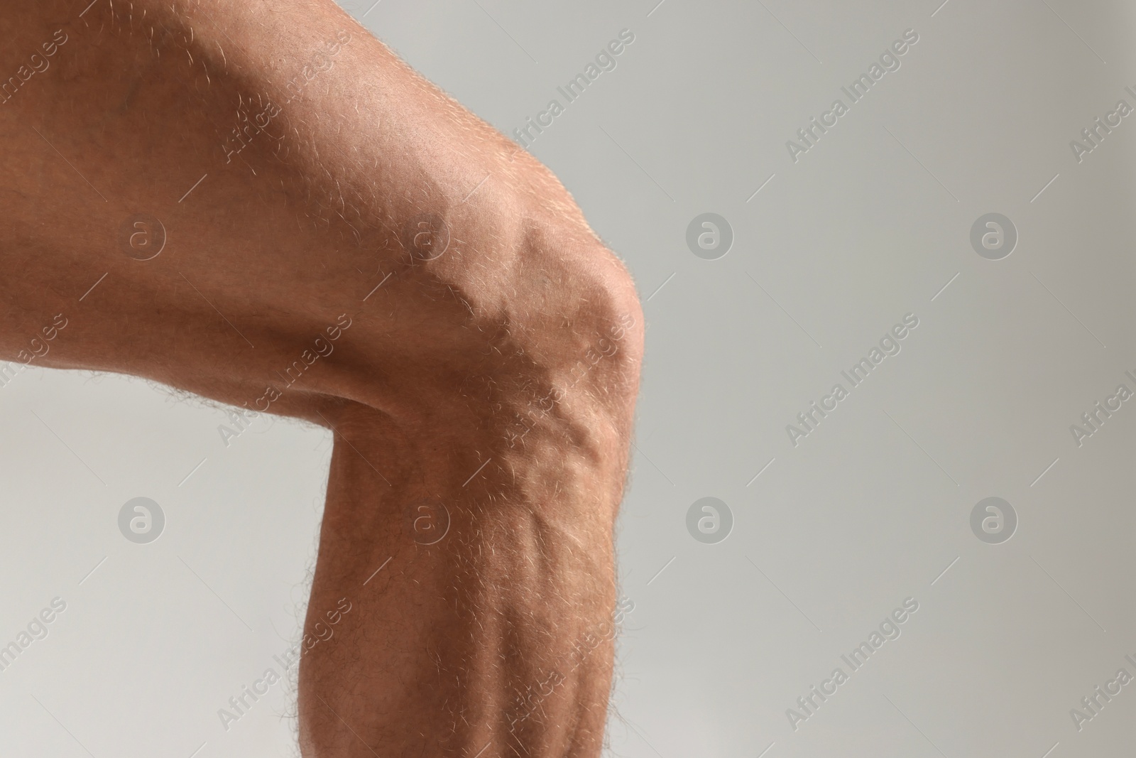 Photo of Man with muscular legs on light grey background, closeup. Space for text