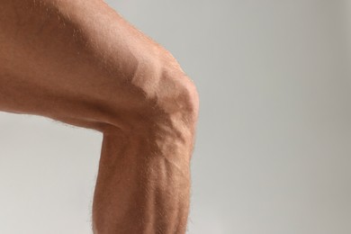 Man with muscular legs on light grey background, closeup. Space for text