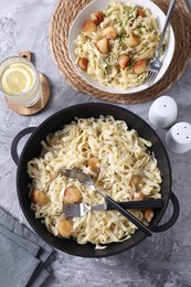 Photo of Delicious scallop pasta with spices in bowl on gray textured table, flat lay