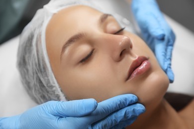 Photo of Young woman receiving facial massage in salon, closeup,