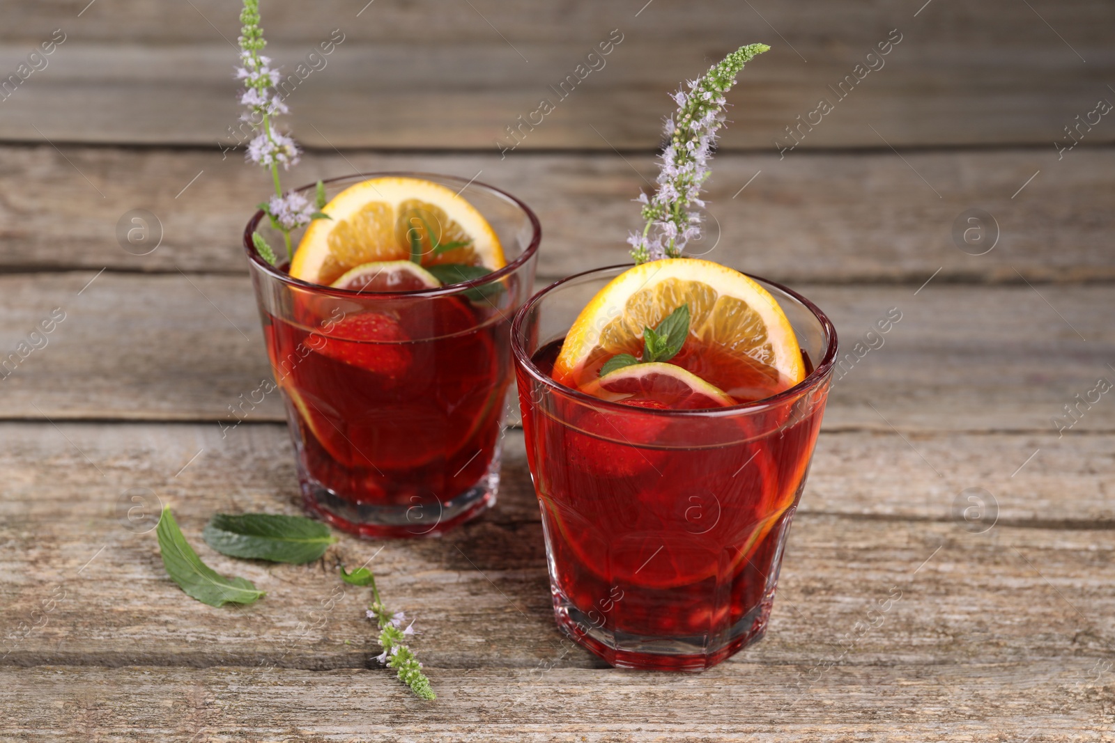 Photo of Glasses of delicious refreshing sangria on old wooden table