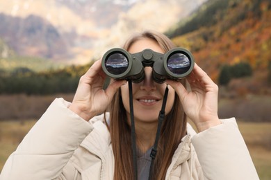 Photo of Woman looking through binoculars in beautiful mountains, closeup