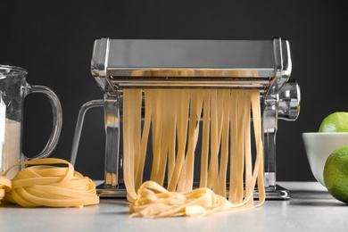 Photo of Pasta maker with dough on kitchen table