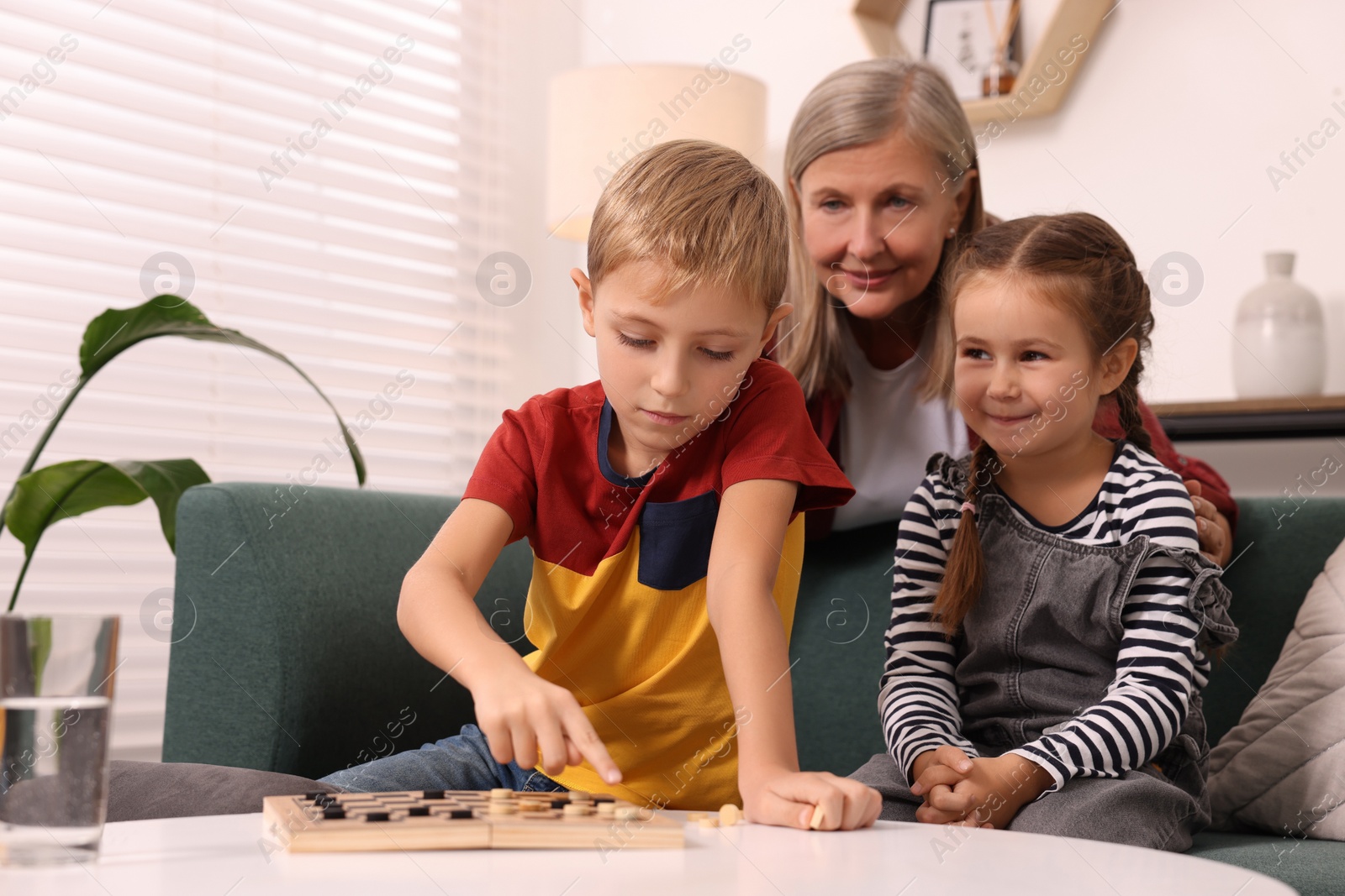 Photo of Family playing checkers at white table in room