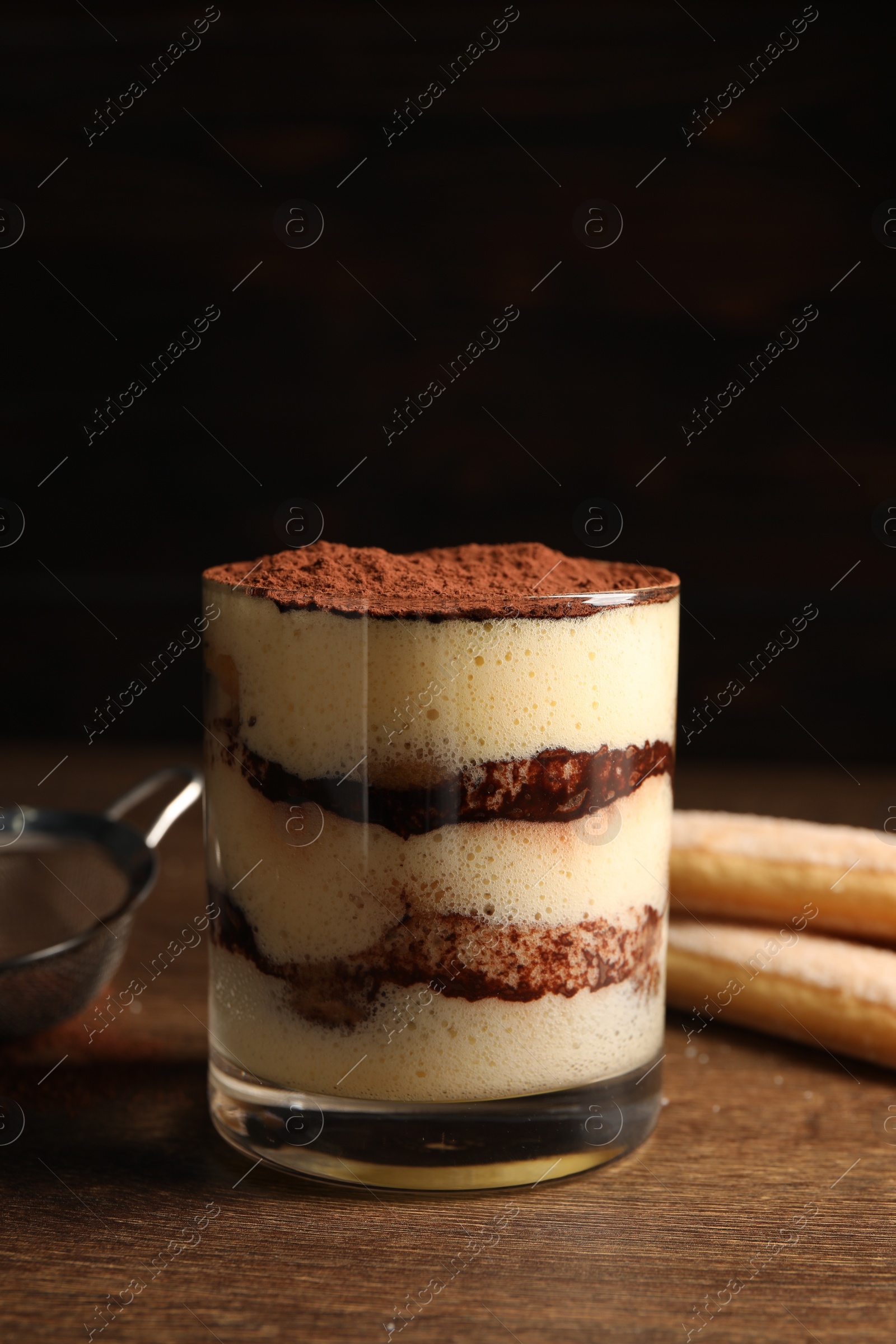 Photo of Delicious tiramisu in glass on wooden table