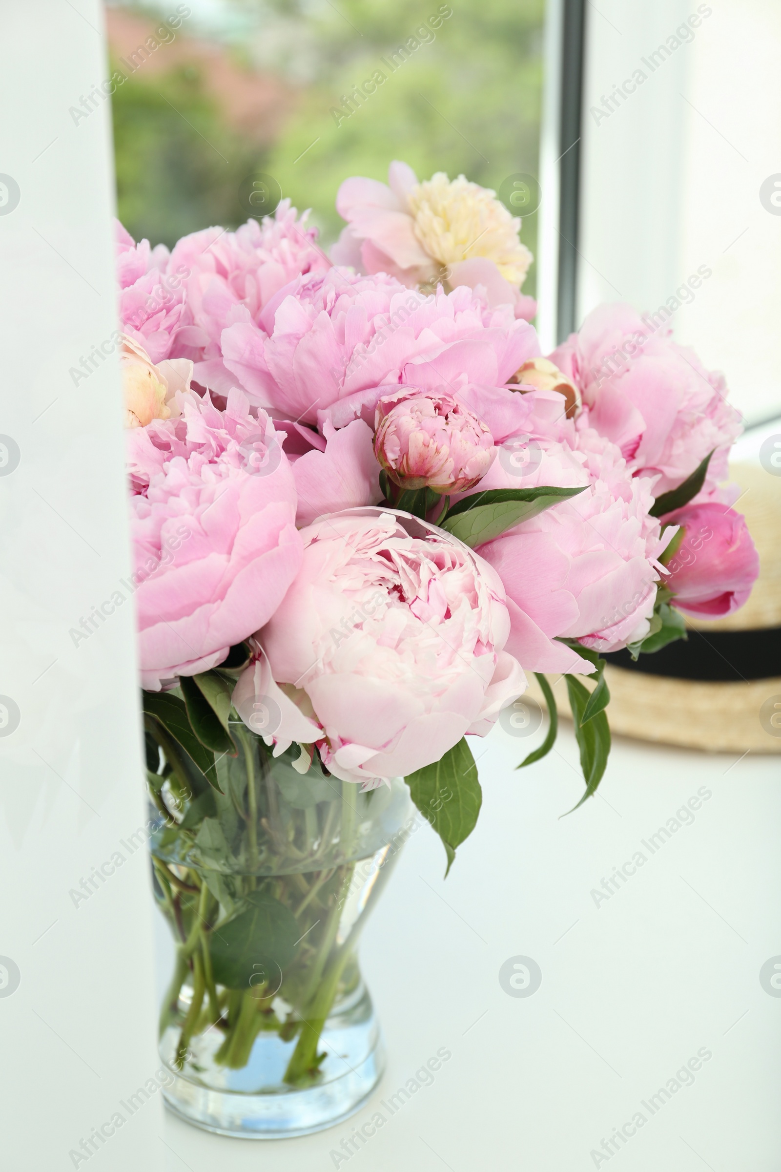 Photo of Bouquet of beautiful peonies in vase on window sill