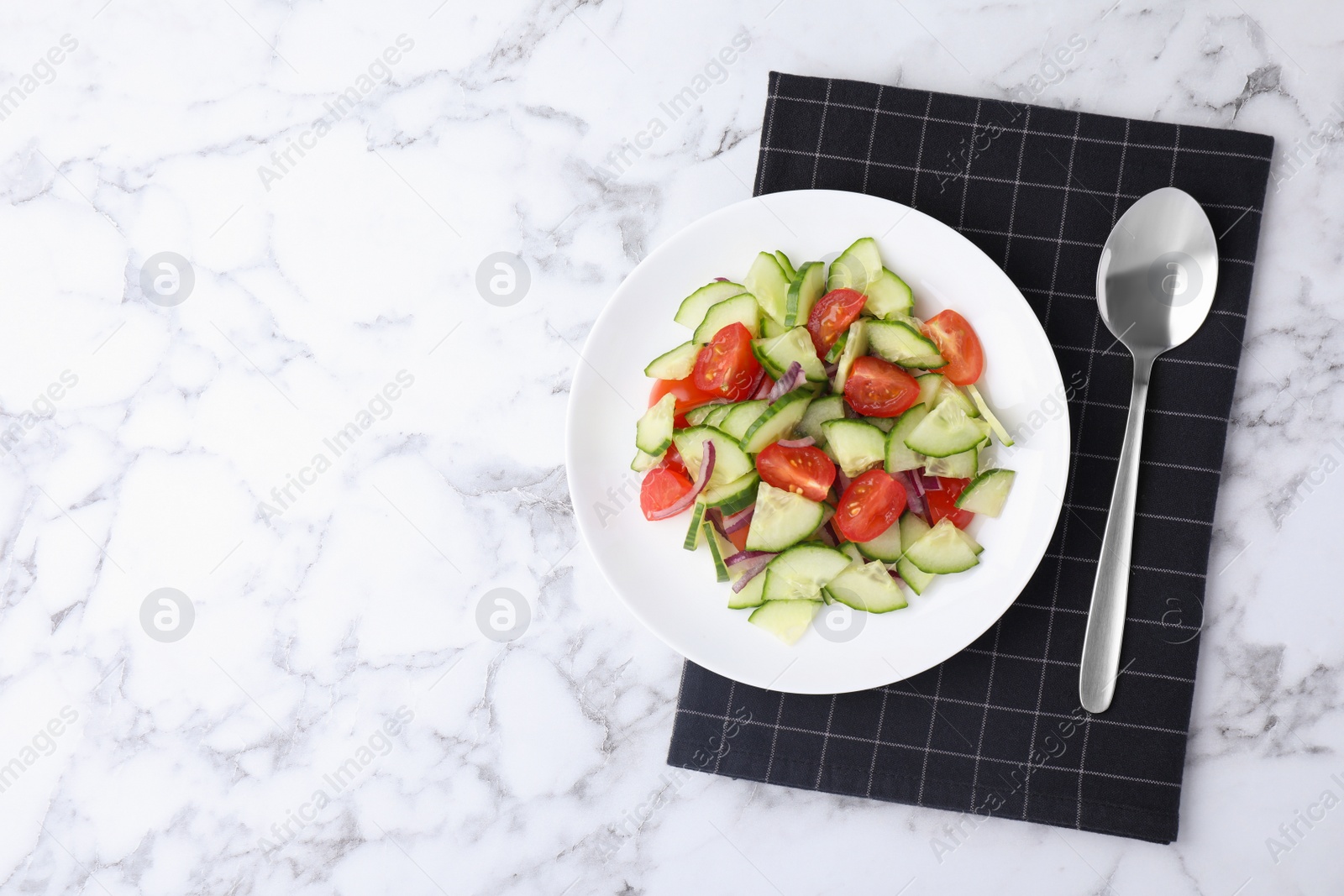 Photo of Plate of vegetarian salad with cucumber, tomato and onion served on table, flat lay. Space for text