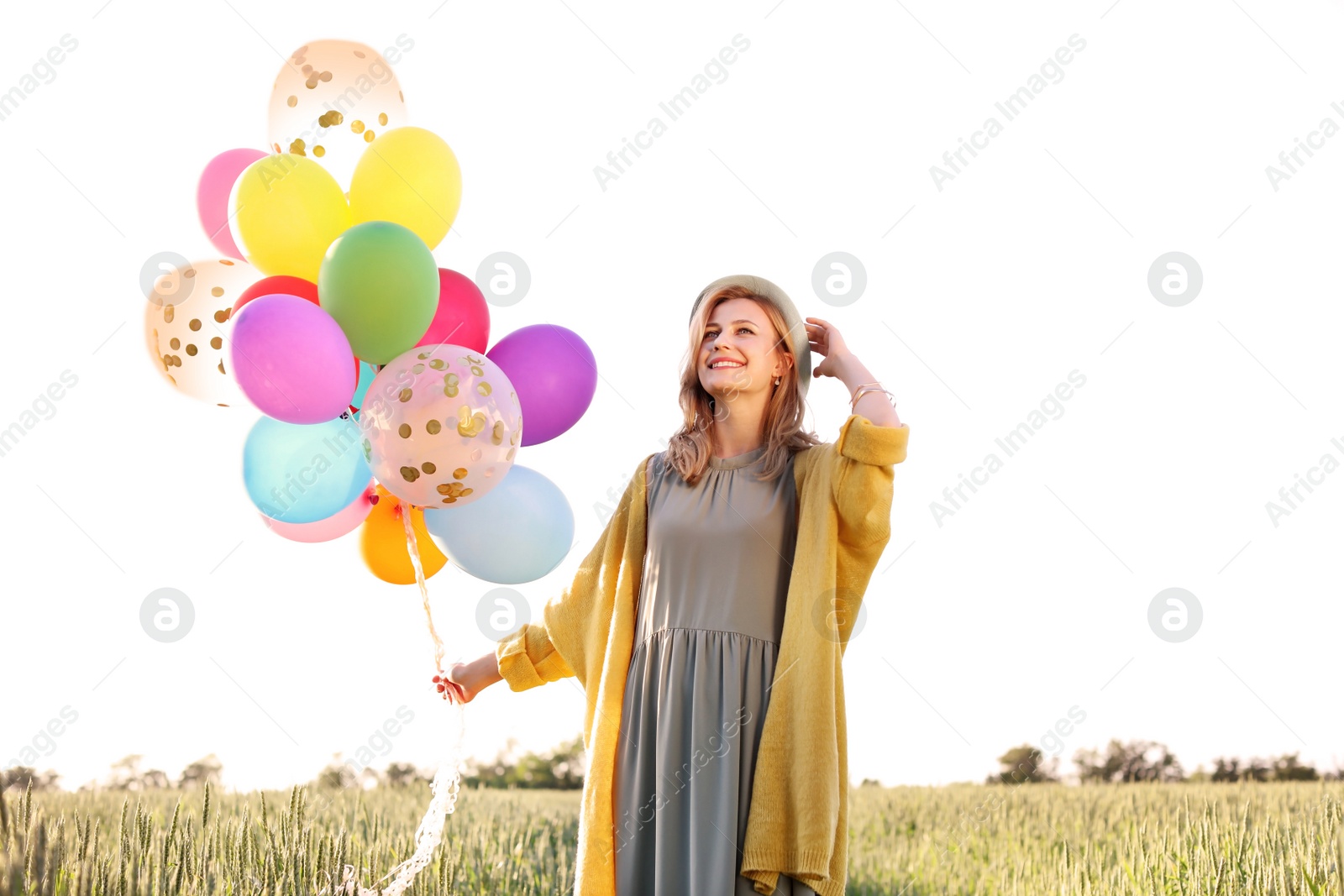 Photo of Young woman with colorful balloons outdoors on sunny day