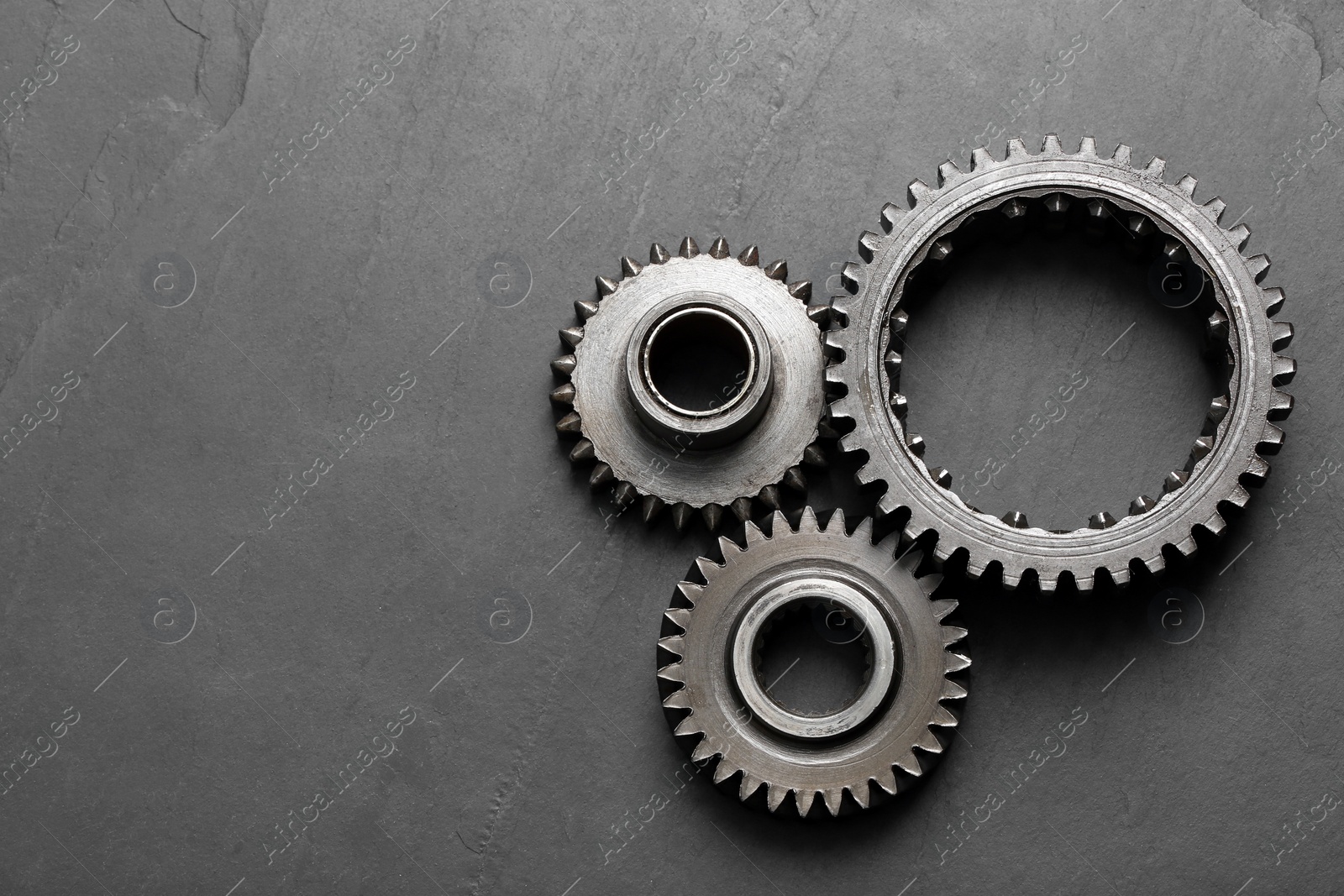 Photo of Different stainless steel gears on grey background, flat lay. Space for text