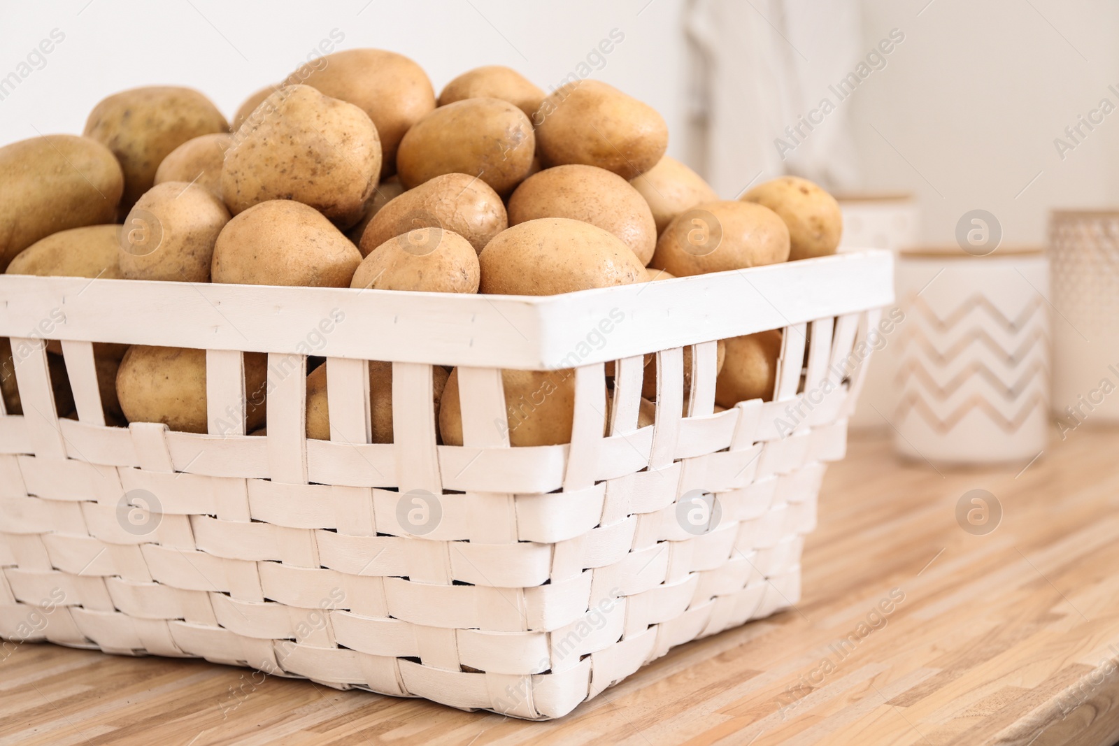 Photo of Basket with potatoes on wooden kitchen counter. Orderly storage