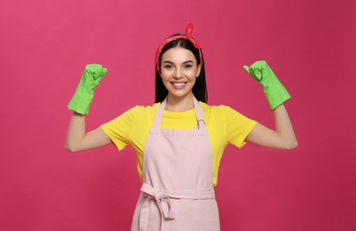 Photo of Young housewife wearing rubber gloves on pink background