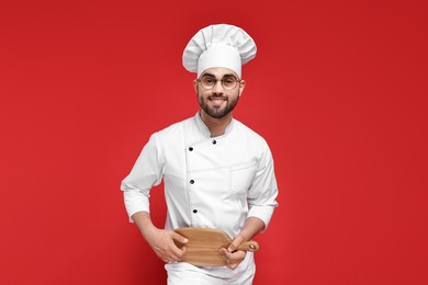 Photo of Professional chef with serving board having fun on red background