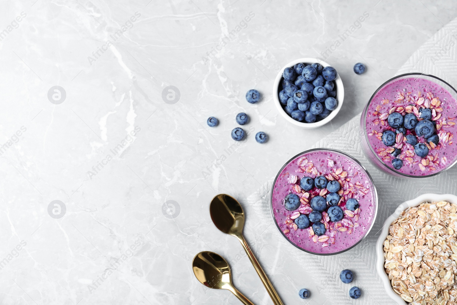 Photo of Tasty blueberry smoothie served on grey table, flat lay. Space for text