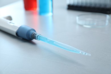 Photo of Laboratory analysis. Micropipette with liquid on grey table, closeup