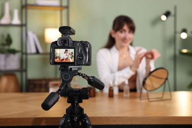 Photo of Beauty blogger recording video while testing cosmetic products at home, focus on camera
