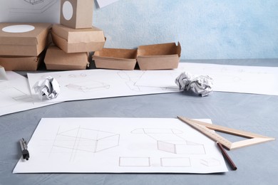 Creating packaging design. Drawings, boxes and stationery on blue textured table, closeup