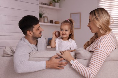 Photo of Family with little daughter spending time together on sofa at home