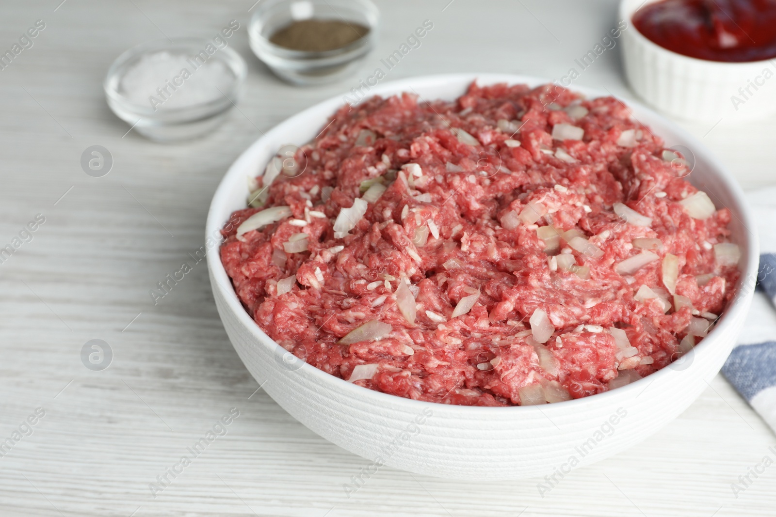 Photo of Meat filling in bowl for stuffed cabbage rolls on white wooden table