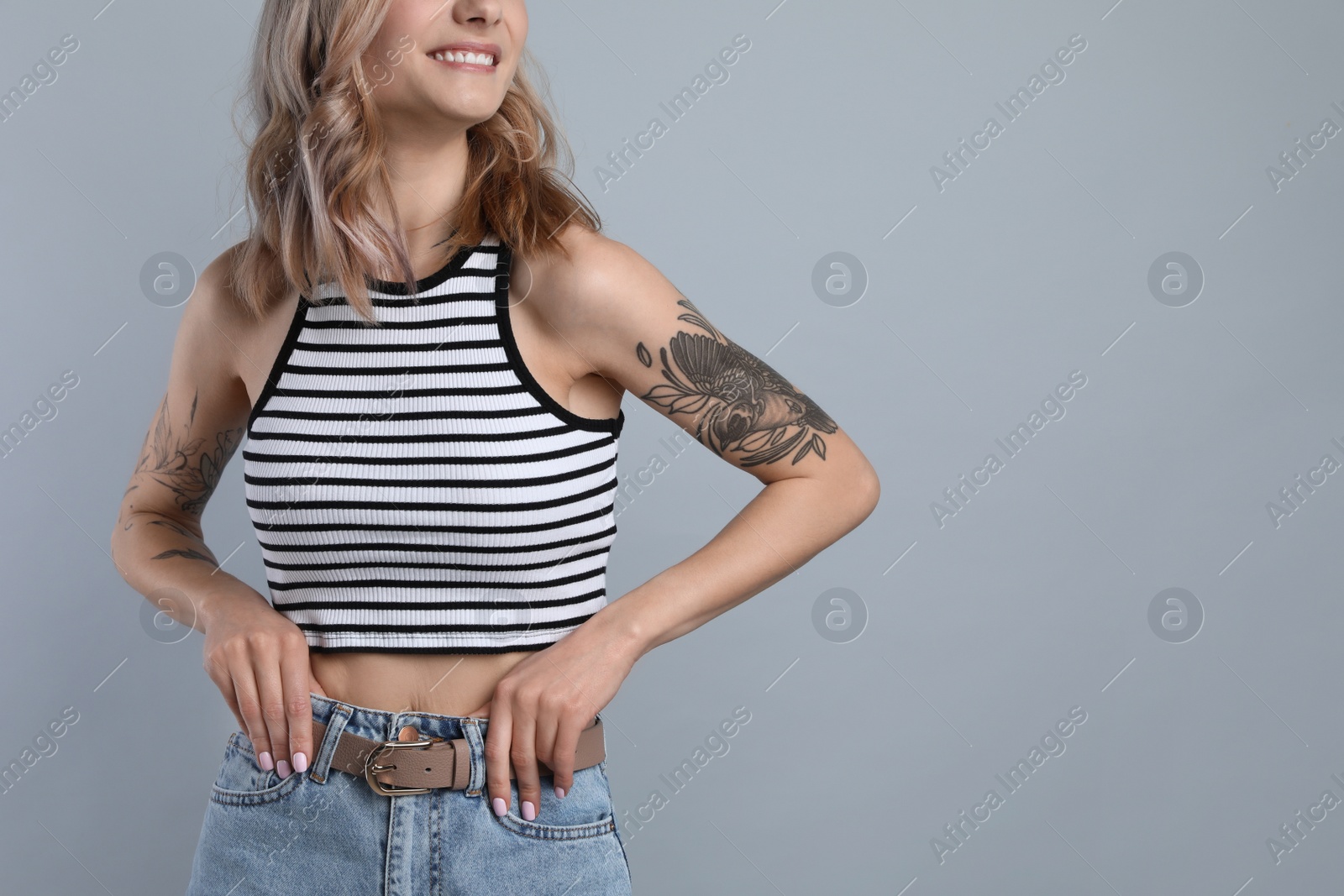 Photo of Beautiful woman with tattoos on body against grey background, closeup. Space for text