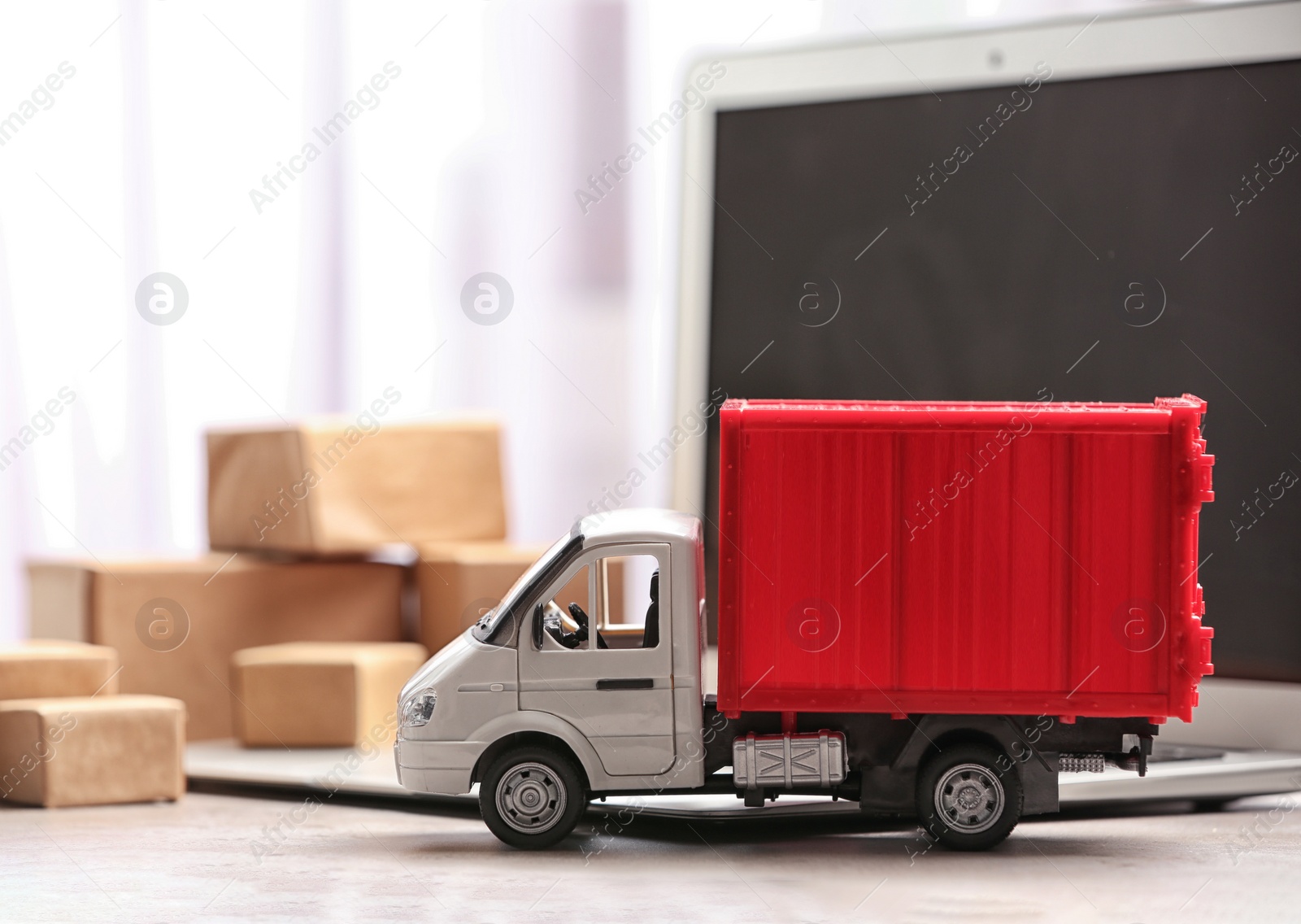 Photo of Toy truck near laptop on table. Logistics and wholesale concept