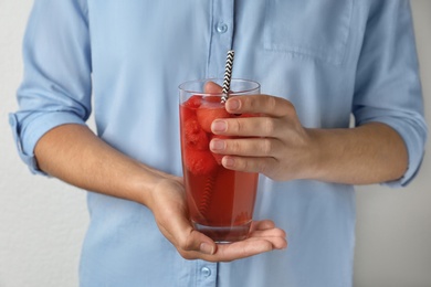 Photo of Woman holding glass of watermelon ball cocktail with straw, closeup