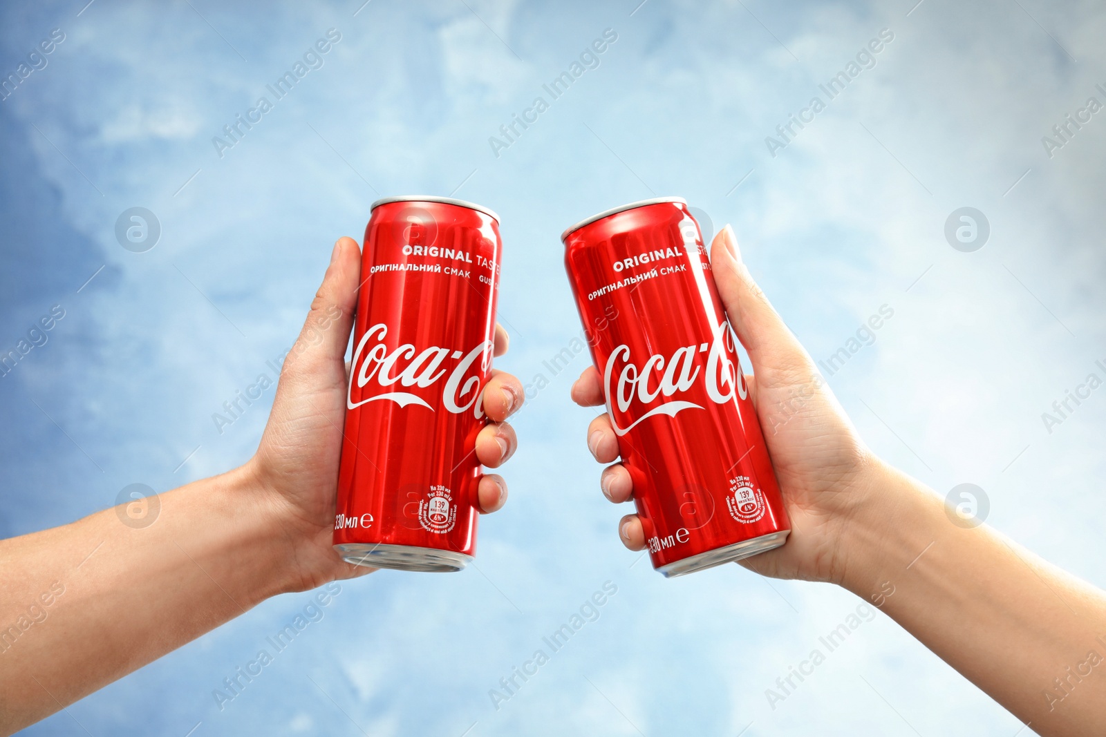 Photo of MYKOLAIV, UKRAINE - NOVEMBER 15, 2018: People with Coca Cola cans on color background, closeup