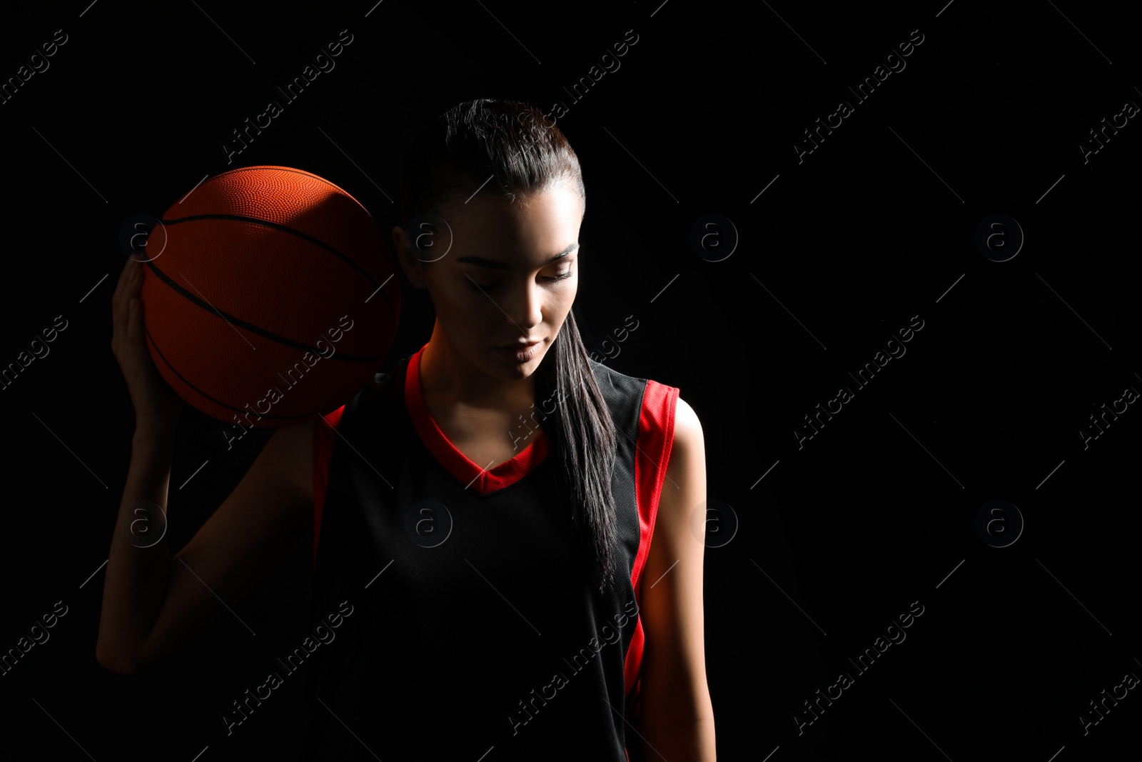 Photo of Basketball player with ball on black background. Space for text
