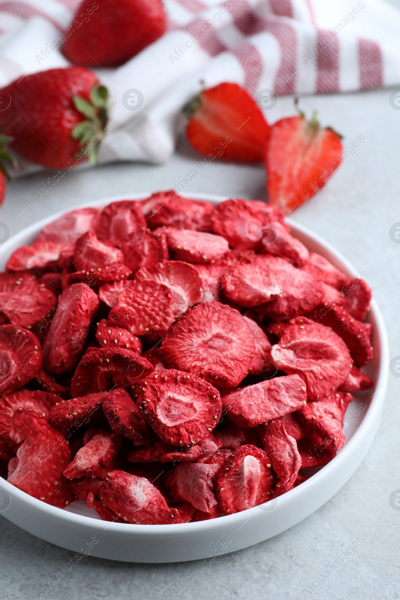 Photo of Freeze dried and fresh strawberries on light grey table, closeup