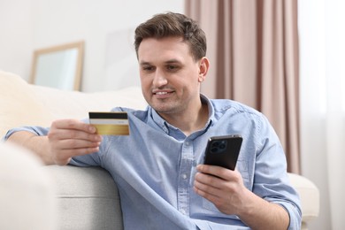 Photo of Man with credit card using smartphone for shopping online at home