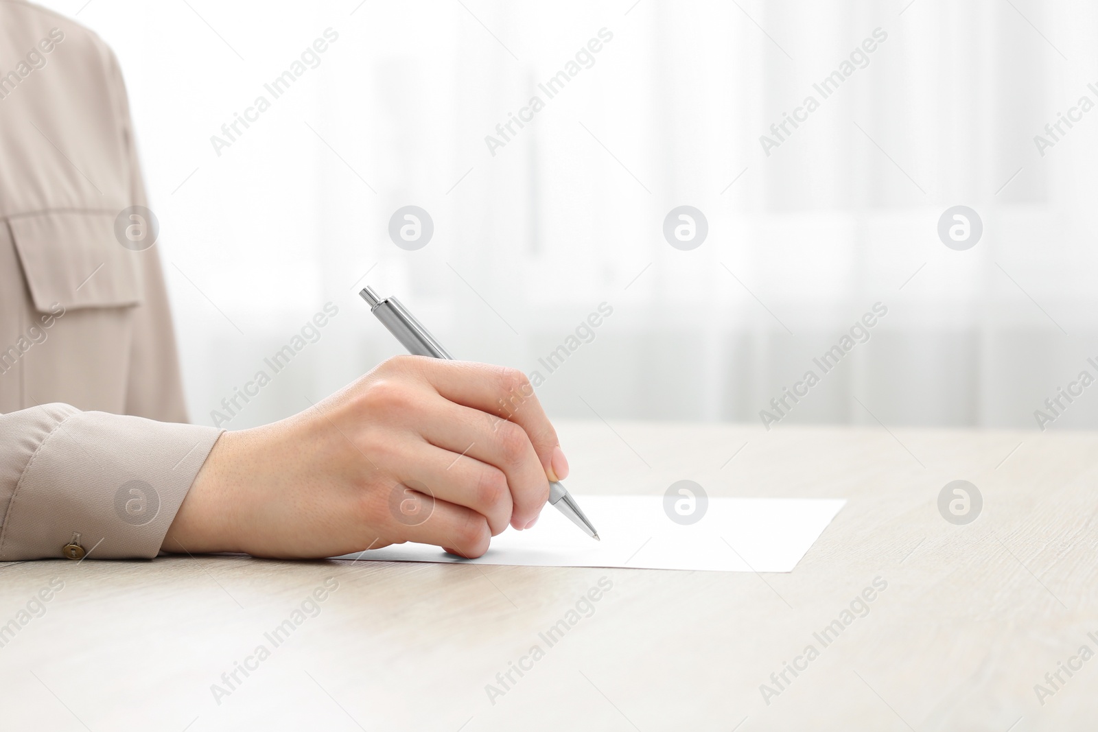 Photo of Woman writing in notebook at wooden table, closeup