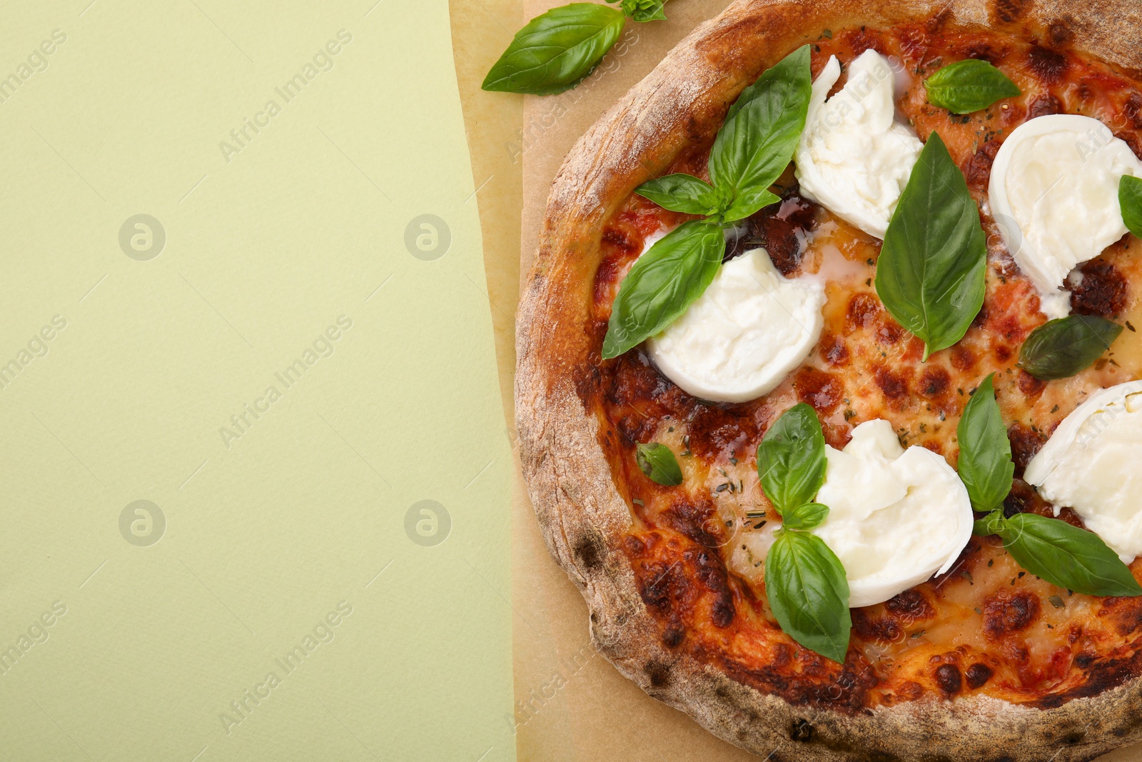 Photo of Delicious pizza with burrata cheese and basil on light green background, top view. Space for text