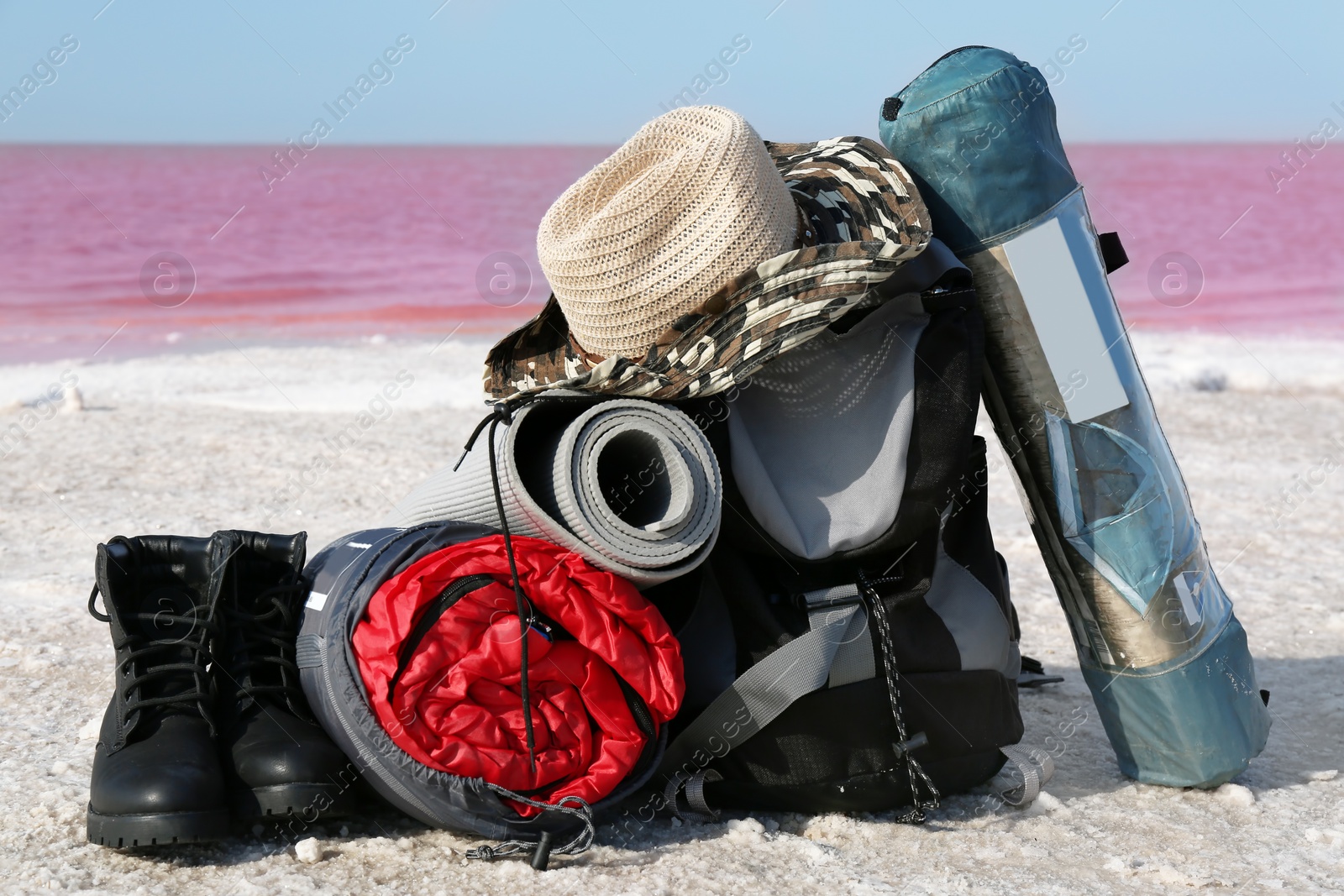 Photo of Set of camping equipment with sleeping bag on coast of pink lake