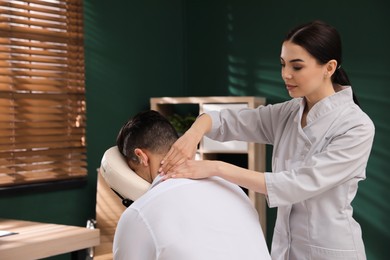 Photo of Man receiving massage in modern chair indoors