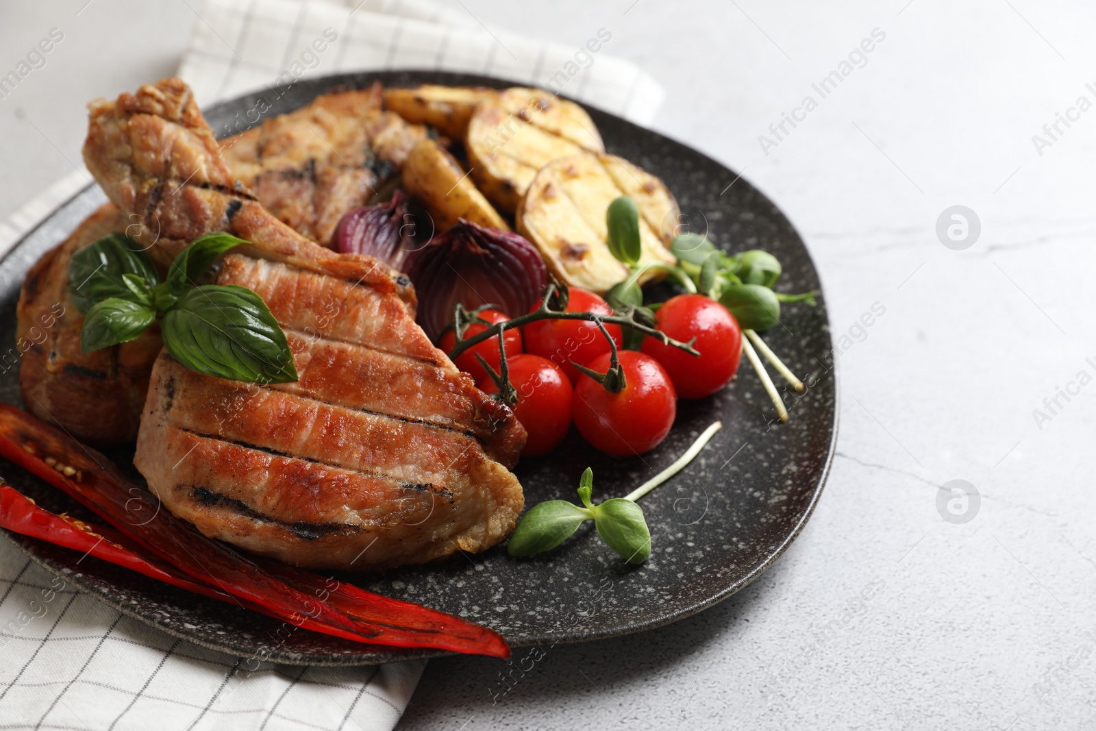 Photo of Delicious grilled meat and vegetables on light grey table, closeup