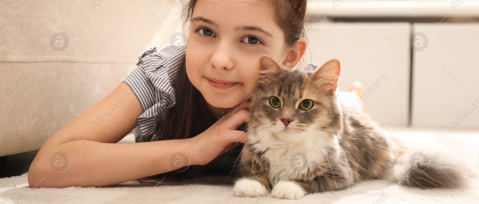 Image of Cute little girl with cat lying on carpet at home. Banner design