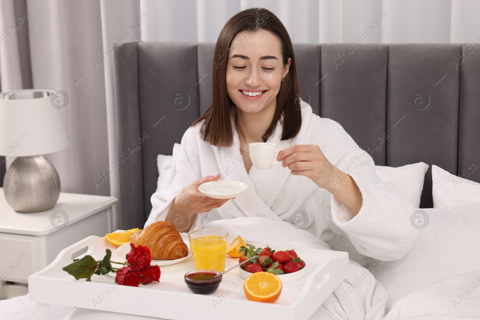 Photo of Smiling woman having breakfast in bed at home