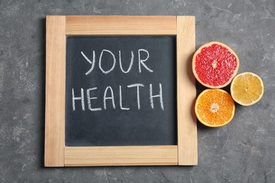 Photo of Chalkboard with words YOUR HEALTH and fruits on grey background, top view. Weight loss concept