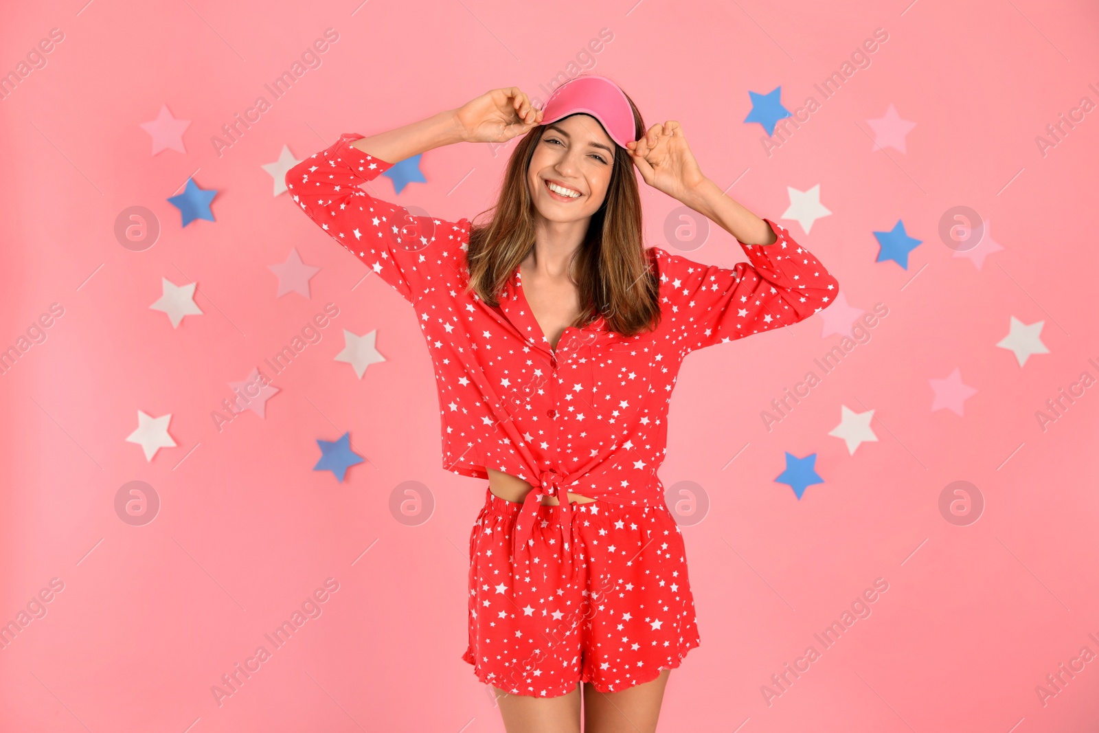 Photo of Beautiful woman wearing pajamas and sleep mask on pink background. Bedtime