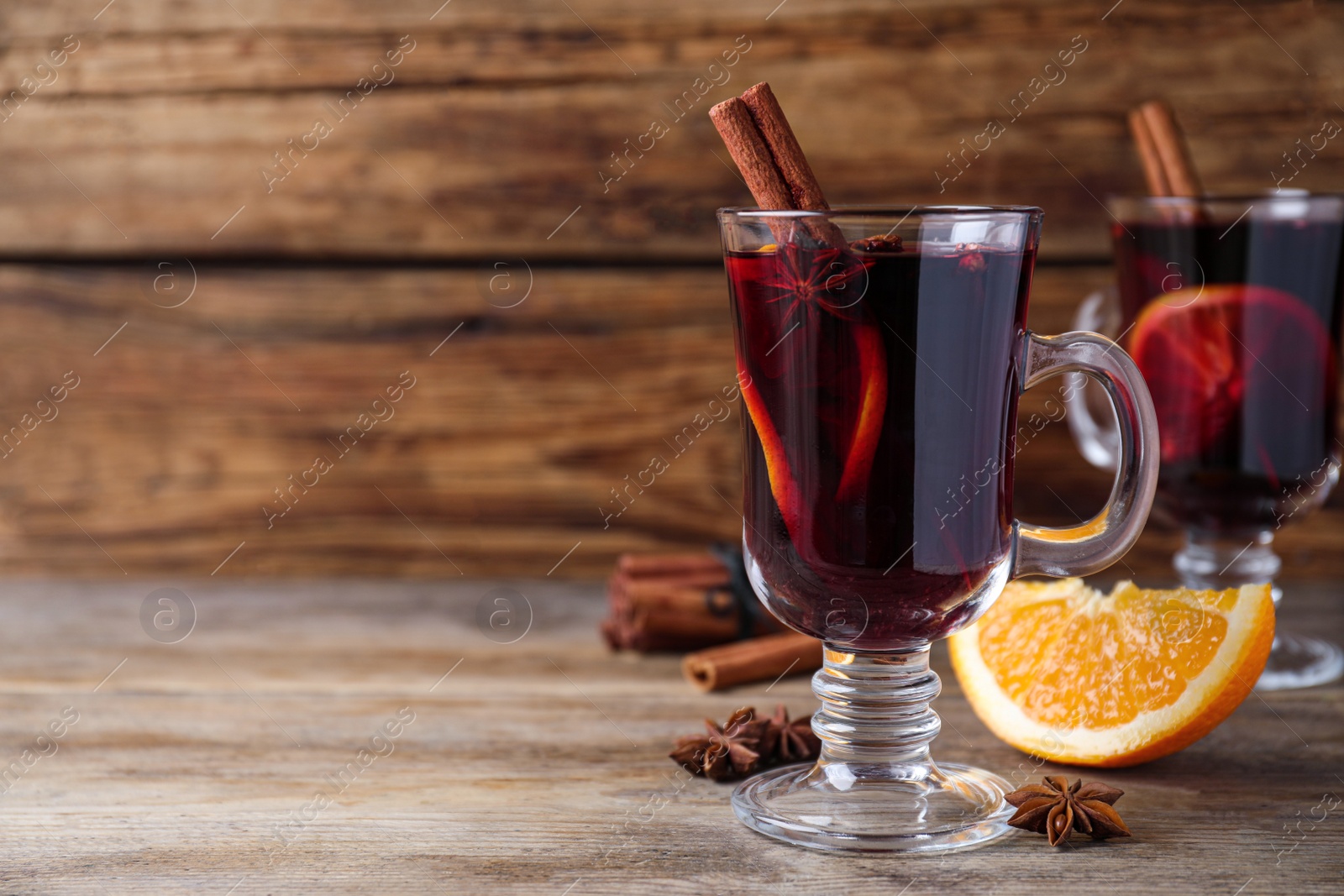 Photo of Delicious red mulled wine on wooden table. Space for text