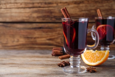 Photo of Delicious red mulled wine on wooden table. Space for text