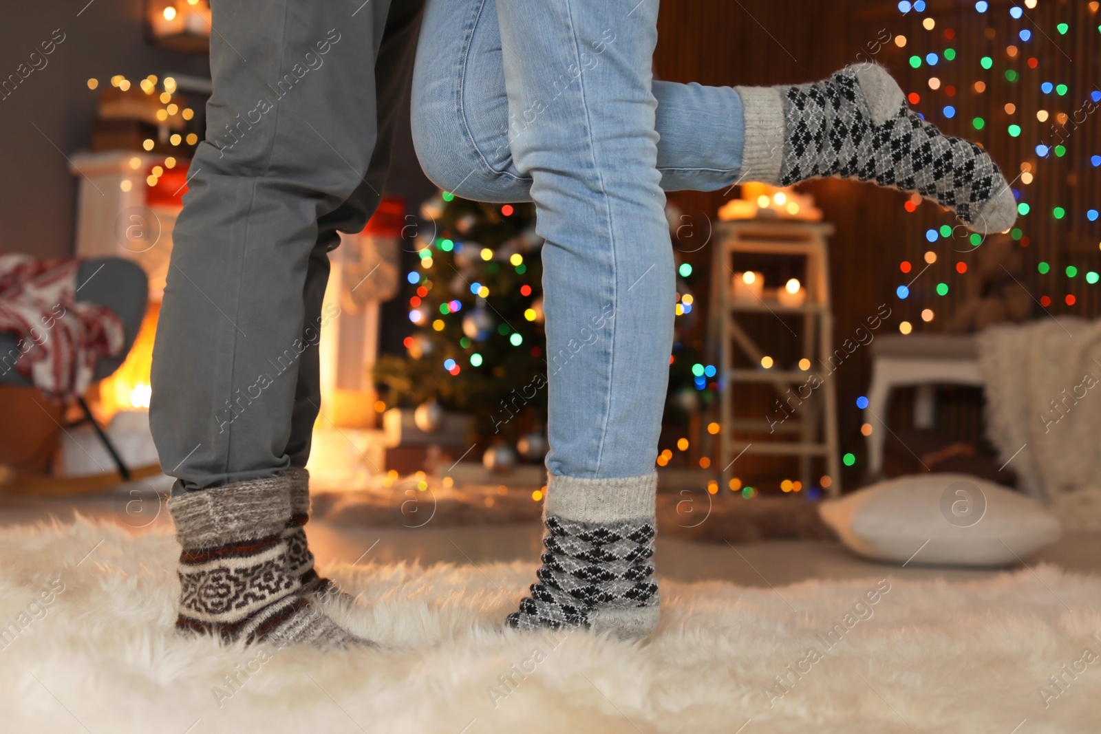 Photo of Young couple in warm socks celebrating Christmas at home