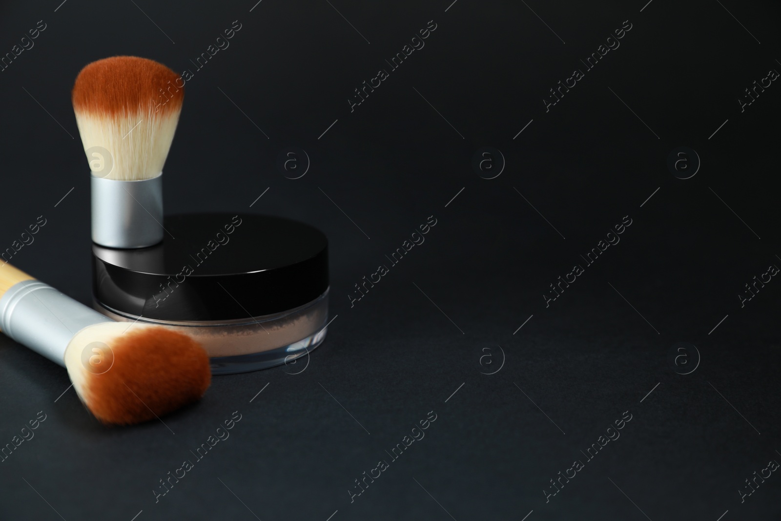 Photo of Face powder and makeup brushes on black background, space for text