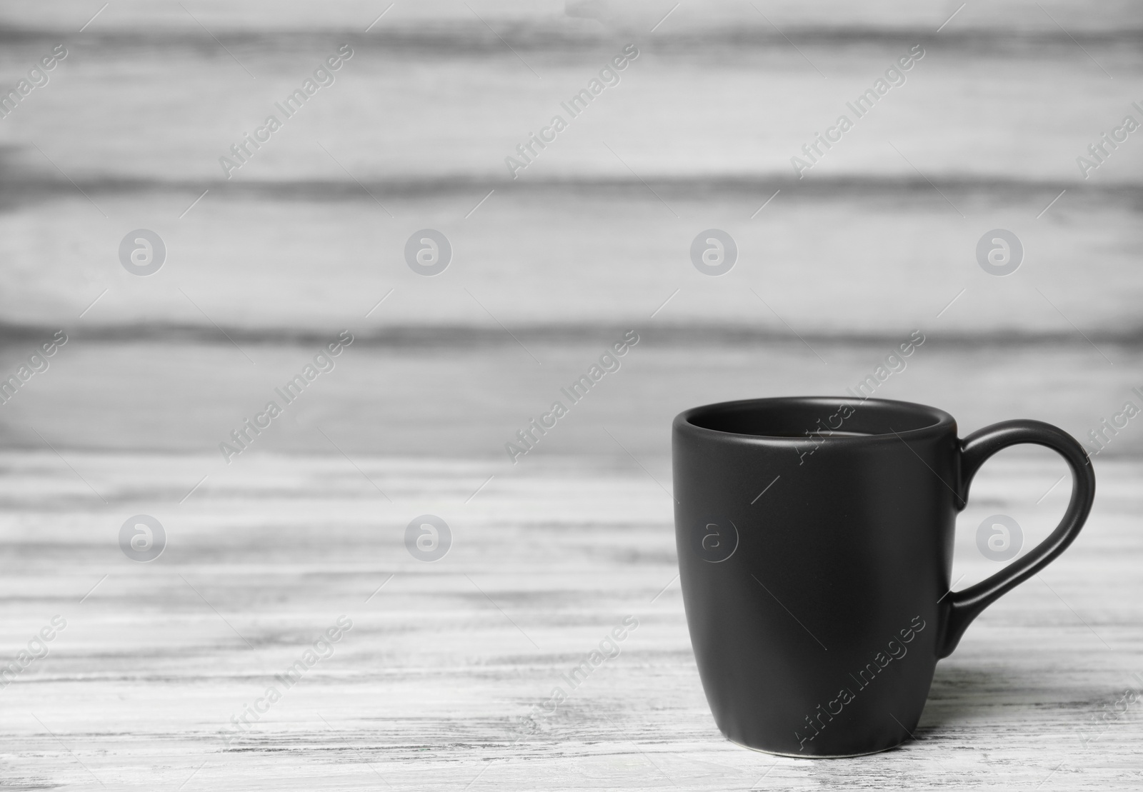 Photo of Black ceramic cup with hot aromatic coffee on table