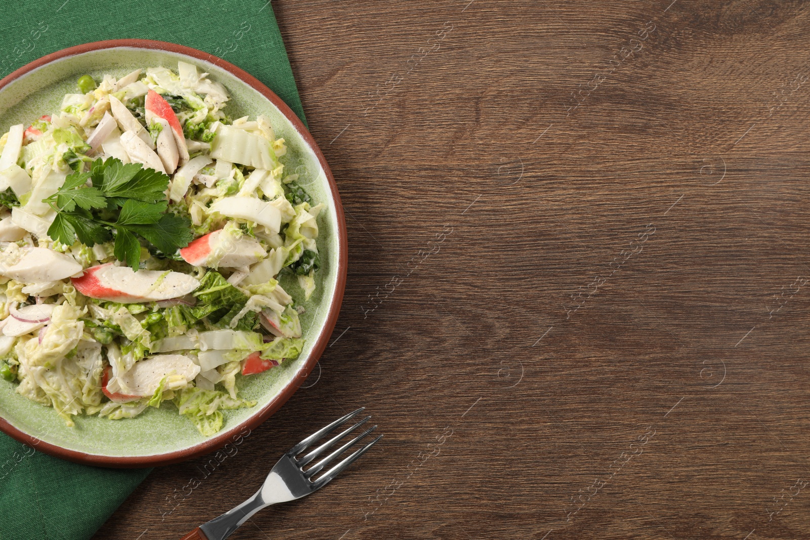 Photo of Delicious salad with Chinese cabbage, crab sticks and parsley on wooden table, top view. Space for text