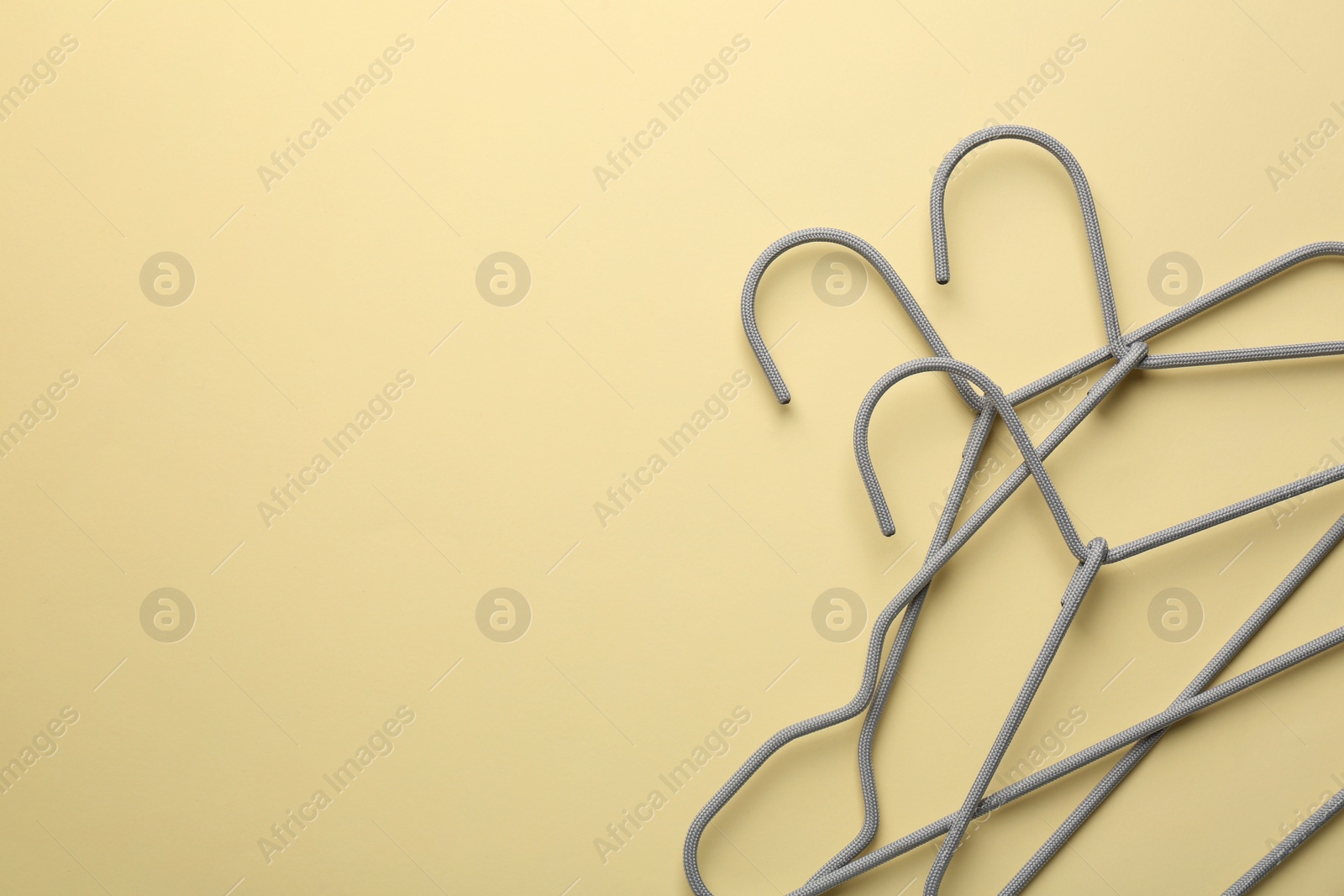 Photo of Hangers on pale yellow background, top view. Space for text