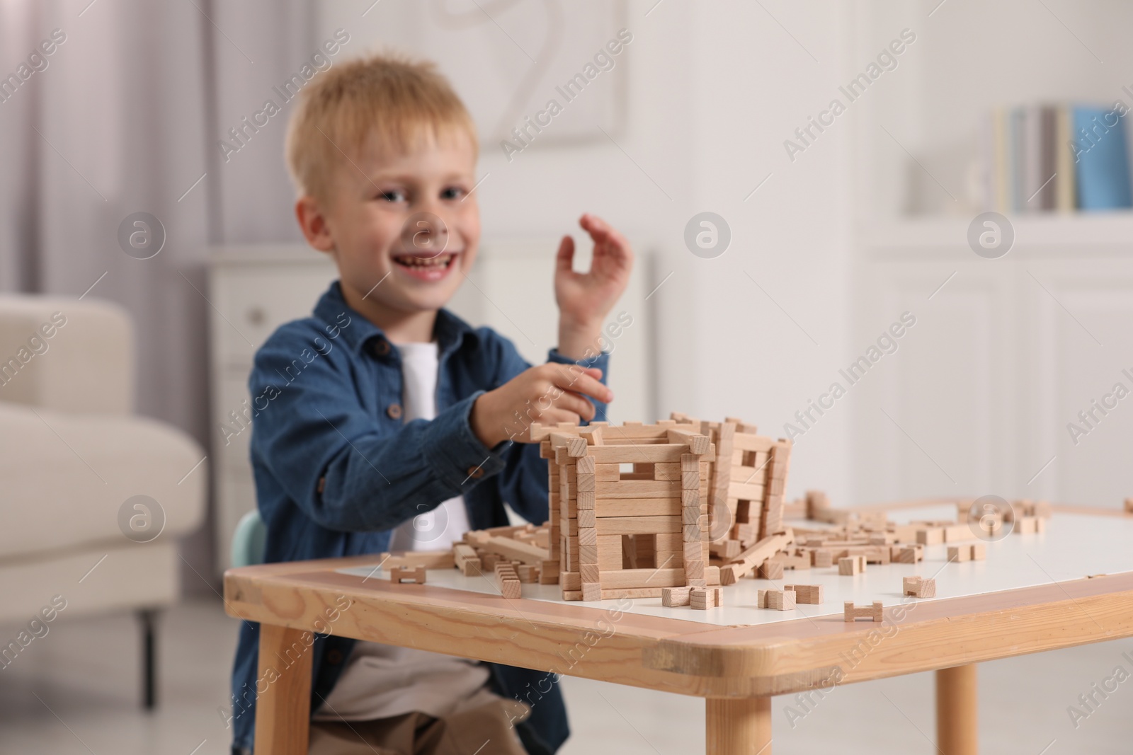 Photo of Cute little boy playing with wooden blocks at table indoors, selective focus. Child's toy